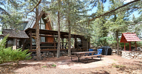 Rustic A-frame cabin rental near Capitol Reef NP, Utah, with a large wooden porch and forest surroundings.
