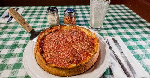 A deep-dish pizza with a glass of water.