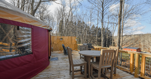 A luxurious maroon and gold glamping yurt with detailed trim, on a teak deck with custom furniture and integrated Maryland-themed text.