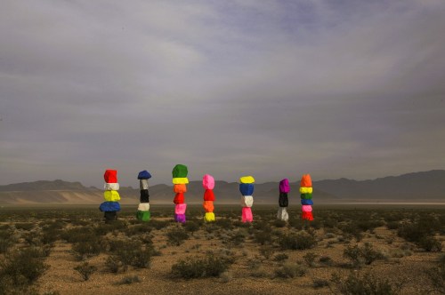 Views of the Seven Magic Mountains art installation near Las Vegas, showing seven rows of colorful stacked rocks against a dark and gloomy backdrop