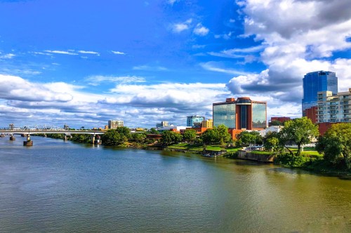 The skyline of Little Rock with the Arkansas River in the foreground under a pretty blue sky