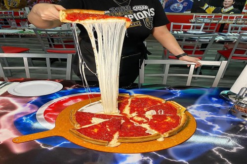 Deep dish Chicago-style pizza showing an extra-long cheese pull