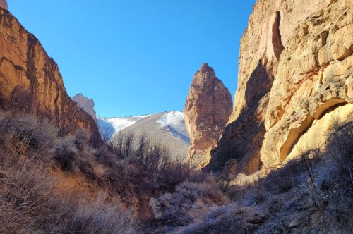 The Leslie Gulch Trail in shade, with the sun illuminating the rock pillars.