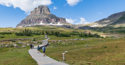 Tourists Hiking On Hidden Lake Trail with Bear Hat Mountain in the Background at Logan Pass, Glacier National Park, Montana.