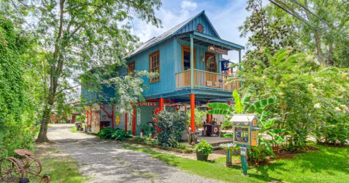 A bright blue and cheerful Airbnb in Louisiana surrounded by green trees.
