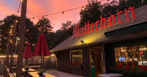 The Matterhorn Mini-Golf course building in Canton, CT at sunset. Several picnic tables with closed umbrellas are in front of the shop.