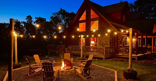 Lit cabin at night in Virginia with a fire pit and wooden deck