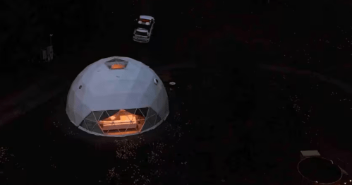 Aerial view of a glowing luxury geodesic dome Airbnb at night in the mountains of New York.