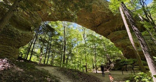 Hiker standing under a giant natural arch in the Big South Fork National River area in Kentucky.