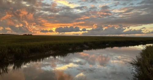 A beautiful sunset is mirrored in a calm river in South Carolina