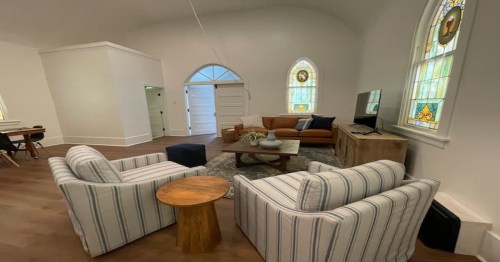 two white and gray striped chairs, a brown couch, and wooden tables in the middle of the living room in an airbnb in wyoming