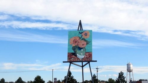 A large easel with a Van Gogh painting on it set against a blue sky