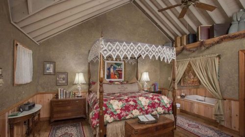 Interior or a unique room from the 7F Lodge in Texas, showing vaulting ceilings and green wallpaper with a canopy bed