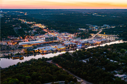 An aeriel view of Branson shows a sunset scene with the lights of the Strip and old downtown along Lake Taneycomo.