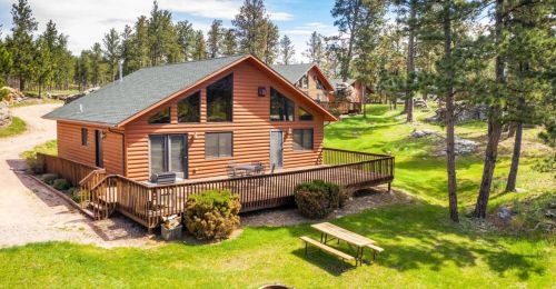 A cabin with a large porch in the woods.
