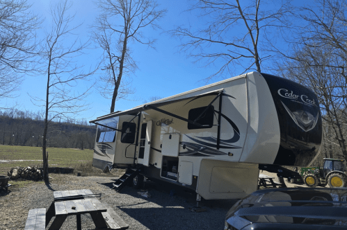 Campground with a large camper, picnic table, and tractor, in Liberty, Kentucky