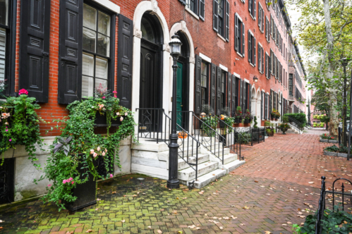 A spring view of a cobblestone street in Philadelphia, Pennsylvania. The street is lined with brick row houses.