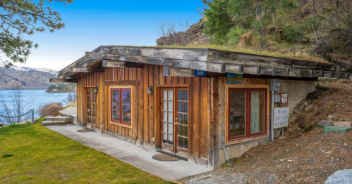 A wood-clad cabin is built into the rugged hillside on the Lake Chelan waterfront.