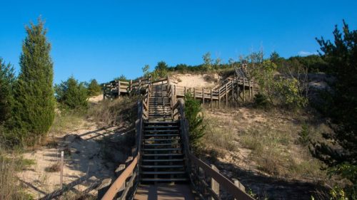 Boardwalk to a sand dune in Gary, Indiana under a bright blue sky