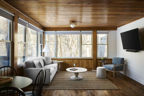 A hotel room with wood paneling overlooking a forest.