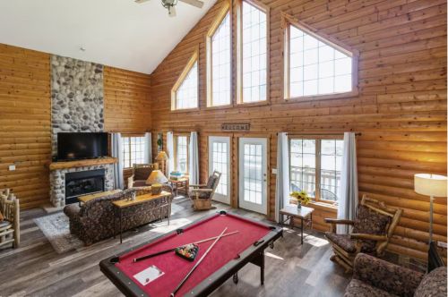 The interior of a cabin with a fireplace and a pool table.