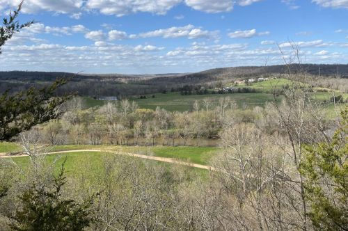 View of green grass, trees, and hills in the background.