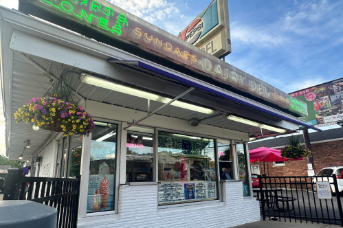 Exterior of a soft serve ice cream shop in Louisville, with pick up windows and a neon sign
