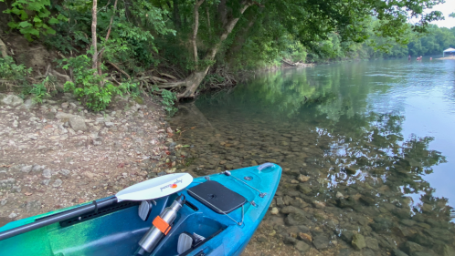 A brightly colored kayak sits on the rocky shores of the Niangua River in Missouri.