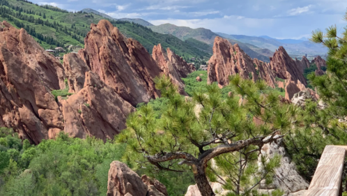 view of red jagged rock formations from an overlook in colorado against a blue summer sky