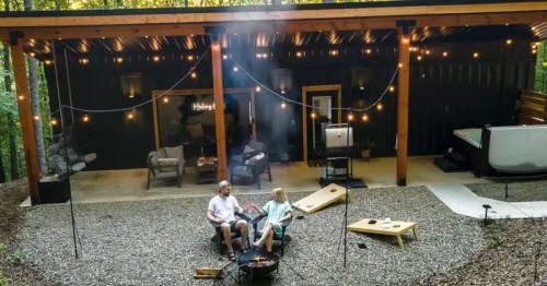 A couple sits in chairs outside of a shipping container Airbnb near Hocking Hills State Park in Ohio.