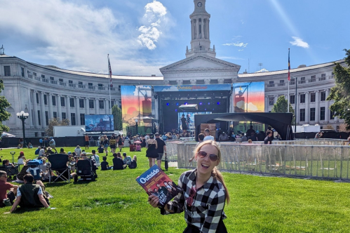 A girl holds a concert program in front of a festival stage
