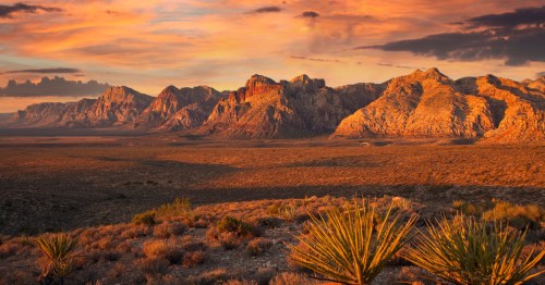 An orange sunrise lights up the Red Rock Canyon Conservation Area in Nevada and the surrounding desert landscape.