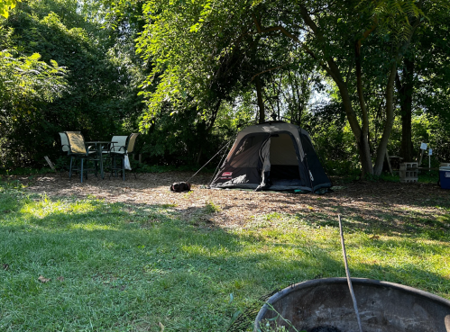 A tent set up with a table and chairs and a fire pit at Willowthorne