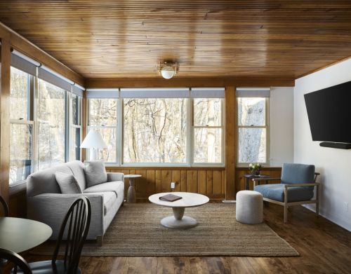 A hotel room with wood paneling overlooking a forest.
