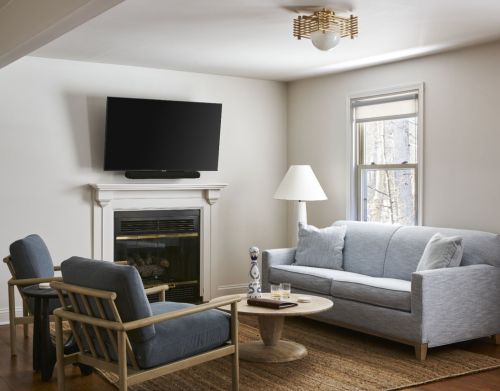 Gray and blue furniture in a white hotel room with a TV.