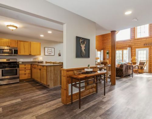 A split view of a kitchen and living room in a large rustic cabin.