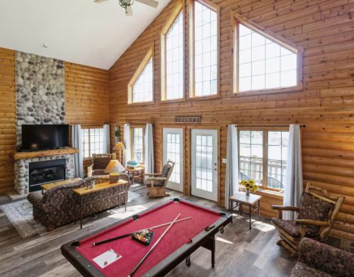 The interior of a cabin with a fireplace and a pool table.
