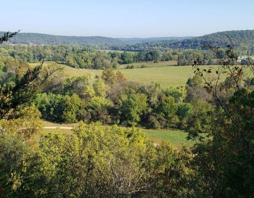 View of green grass, trees, and hills in the background.