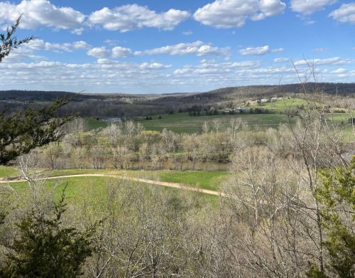 View of green grass, trees, and hills in the background.