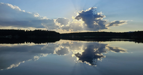 Clouds reflect on a glassy lake in the early evening at Custer State Park, South Dakota.