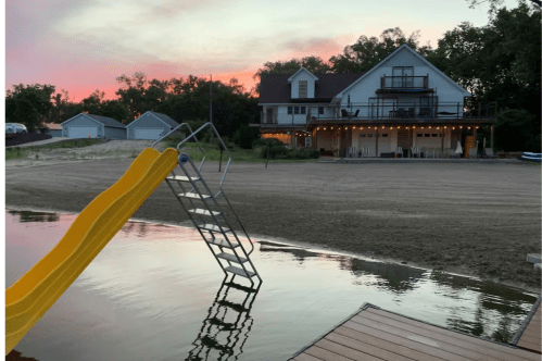 The Crappie Cove Airbnb with a sunset in the background and the lake with slide in the foreground.