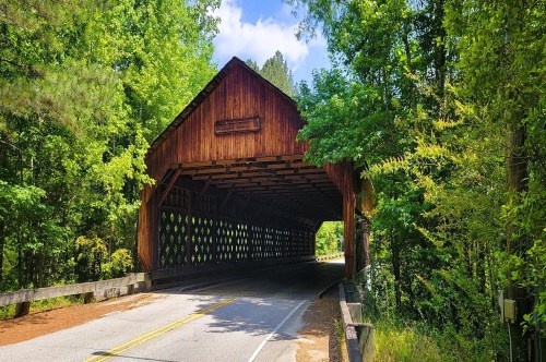 A unique wooden, covered bridge near Atlanta is surrounded by lush greenery.