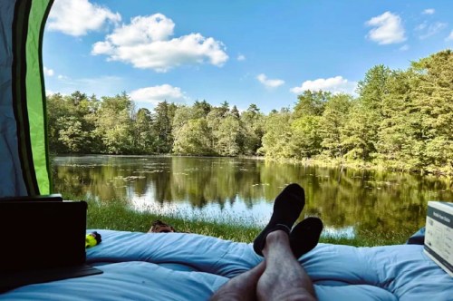 View from inside a tent of a scenic lake surrounded by trees at a waterfront campground in New Jersey.