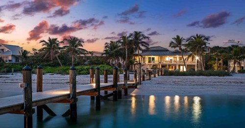a lakefront Airbnb home in Florida with a private dock on the water and a pink and purple sunset above