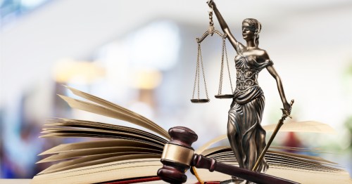 The scales of justice, a gaval, and a book displayed in a judicial scene.