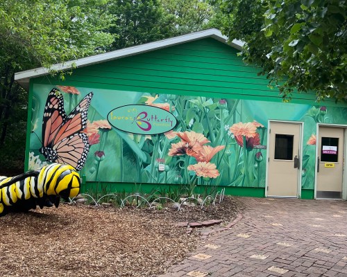 Laura's Butterfly Pavilion at Lincoln Children's Zoo with a caterpillar statue on the left side.