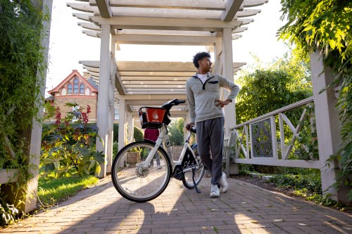 A man with a bicycle on a brick pathway in the Allen Centennial Garden