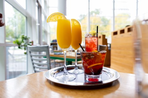 A silver tray with four beverages on a table facing the windows at Graze in Madison