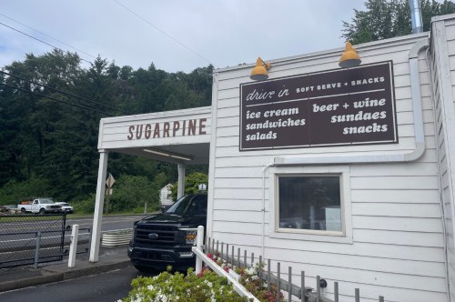 A white building with a sugarpine drive-in sign containing what the restaurant sells.