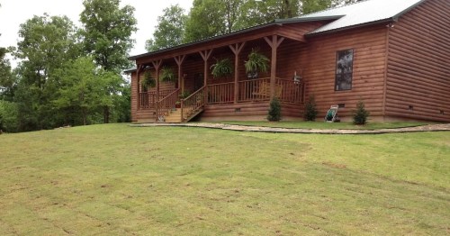 a wooden log-cabin exterior of a mississippi airbnb with a large patch of grass in front